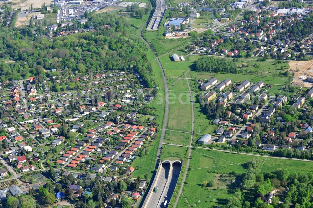 Aerial photograph Berlin - Part of the federal motorway A113 in the Altglienicke part of the borough of Treptow-Koepenick in Berlin in Germany. The motorway takes its course through a tunnel on the western edge of Altglienicke and the Eastern edge of the Rudower Hoehe area. The wooded area consists of residential buildings, allotements and estates. View from the South