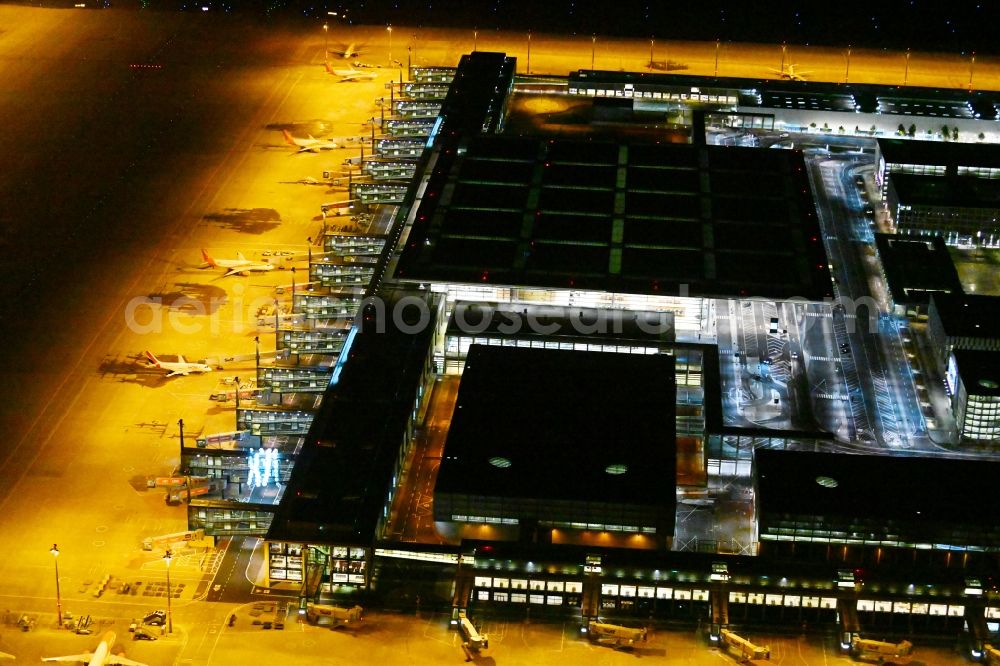 Aerial image at night Schönefeld - Night lighting dispatch building and terminals on the premises of the airport BER in Schoenefeld in the state Brandenburg