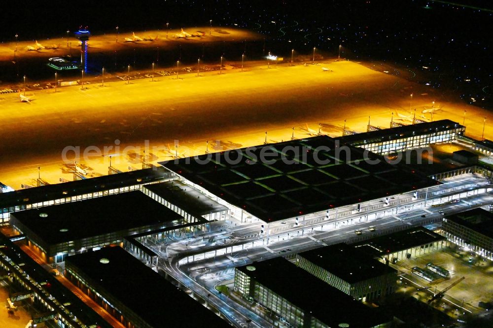 Aerial photograph at night Schönefeld - Night lighting dispatch building and terminals on the premises of the airport BER in Schoenefeld in the state Brandenburg