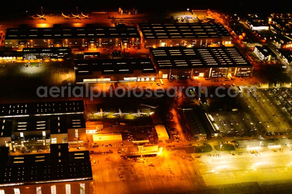 Aerial image at night Hamburg - Night lighting airbus works and airport of Finkenwerder in Hamburg in Germany. The former Hamburger Flugzeugbau works - on the Finkenwerder Peninsula on the riverbank of the Elbe - include an Airbus production site with an airplane. Several Airbus planes and models are being constructed here