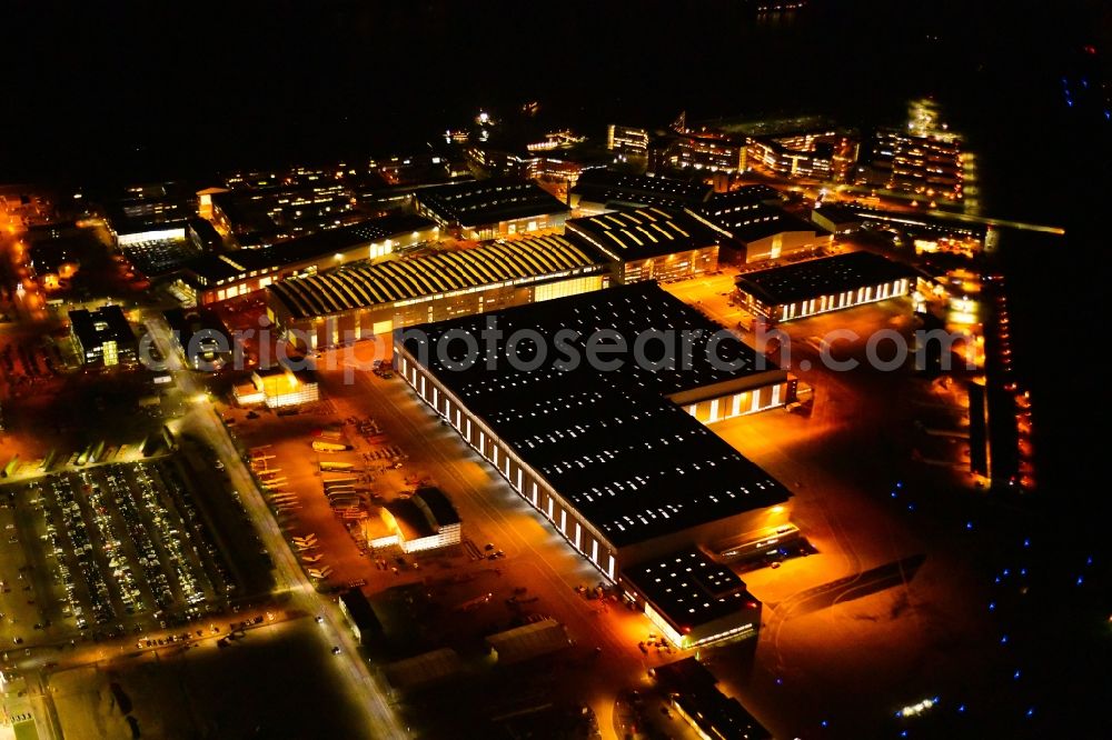 Hamburg at night from above - Night lighting airbus works and airport of Finkenwerder in Hamburg in Germany. The former Hamburger Flugzeugbau works - on the Finkenwerder Peninsula on the riverbank of the Elbe - include an Airbus production site with an airplane. Several Airbus planes and models are being constructed here