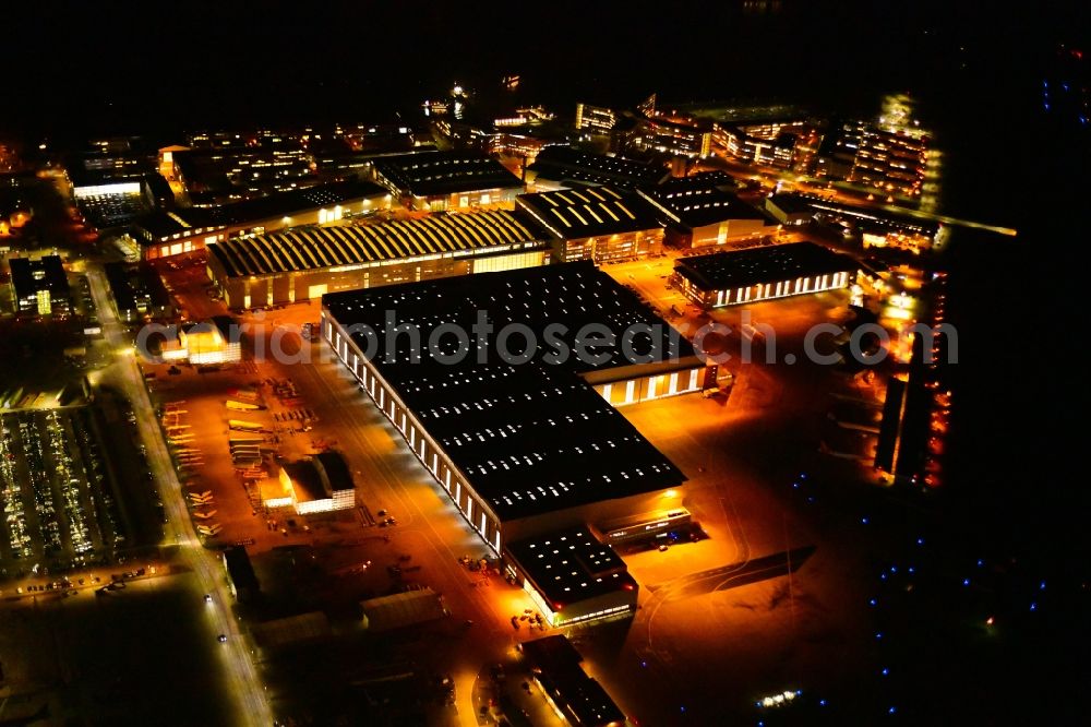 Hamburg at night from the bird perspective: Night lighting airbus works and airport of Finkenwerder in Hamburg in Germany. The former Hamburger Flugzeugbau works - on the Finkenwerder Peninsula on the riverbank of the Elbe - include an Airbus production site with an airplane. Several Airbus planes and models are being constructed here