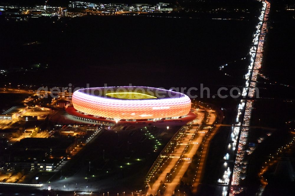 München at night from above - Night lighting the Allianz Arena in Munich in Bavaria is a football stadium of the the Munich football club FC Bayern Muenchen. The facade of the, designed by the architects Herzog & de Meuron stadium Allianz Arena Muenchen Stadion GmbH consists of illuminated white foil cushions
