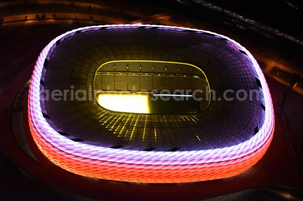 Aerial photograph at night München - Night lighting the Allianz Arena in Munich in Bavaria is a football stadium of the the Munich football club FC Bayern Muenchen. The facade of the, designed by the architects Herzog & de Meuron stadium Allianz Arena Muenchen Stadion GmbH consists of illuminated white foil cushions