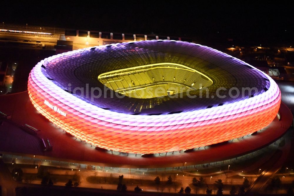 München at night from above - Night lighting the Allianz Arena in Munich in Bavaria is a football stadium of the the Munich football club FC Bayern Muenchen. The facade of the, designed by the architects Herzog & de Meuron stadium Allianz Arena Muenchen Stadion GmbH consists of illuminated white foil cushions