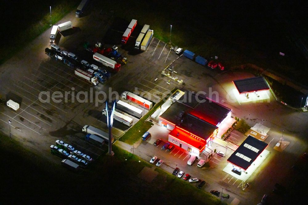 Landsberg at night from the bird perspective: Night lighting Routing and traffic lanes during the motorway service station and parking lot of the BAB A 14 TOTAL Autohof in Landsberg in the state Saxony-Anhalt, Germany