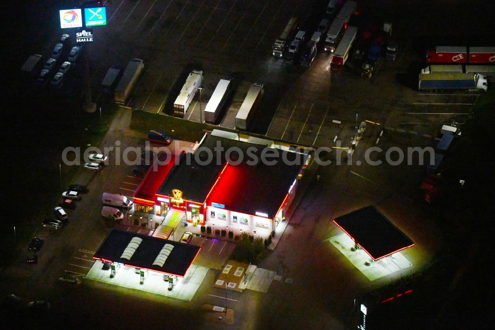 Aerial image at night Landsberg - Night lighting Routing and traffic lanes during the motorway service station and parking lot of the BAB A 14 TOTAL Autohof in Landsberg in the state Saxony-Anhalt, Germany