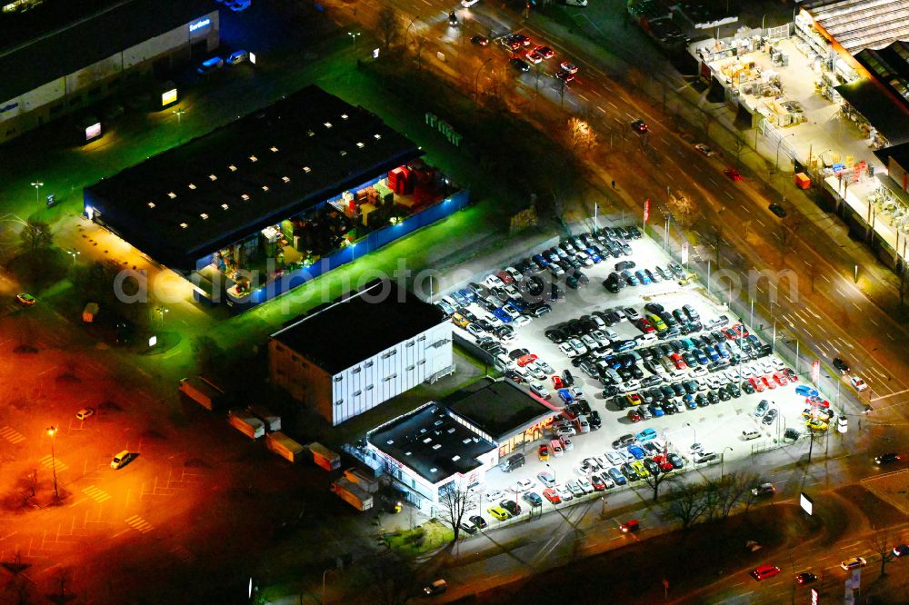 Aerial image at night Berlin - Night lighting car dealership building of Autoland AG on street Nonnendammallee in the district Spandau in Berlin, Germany