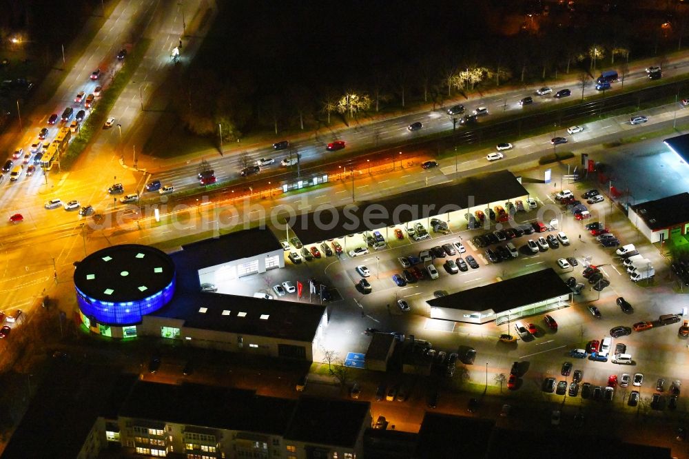 Berlin at night from the bird perspective: Night lighting car dealership building PEUGEOT PSA RETAIL on Blumberger Donm corner Landsberger Allee in the district Marzahn in Berlin, Germany