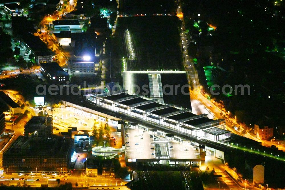 Aerial image at night Berlin - Night lighting Station building and track systems of the S-Bahn station Berlin Suedkreuz on motorway A100 in the district Tempelhof-Schoeneberg in Berlin, Germany