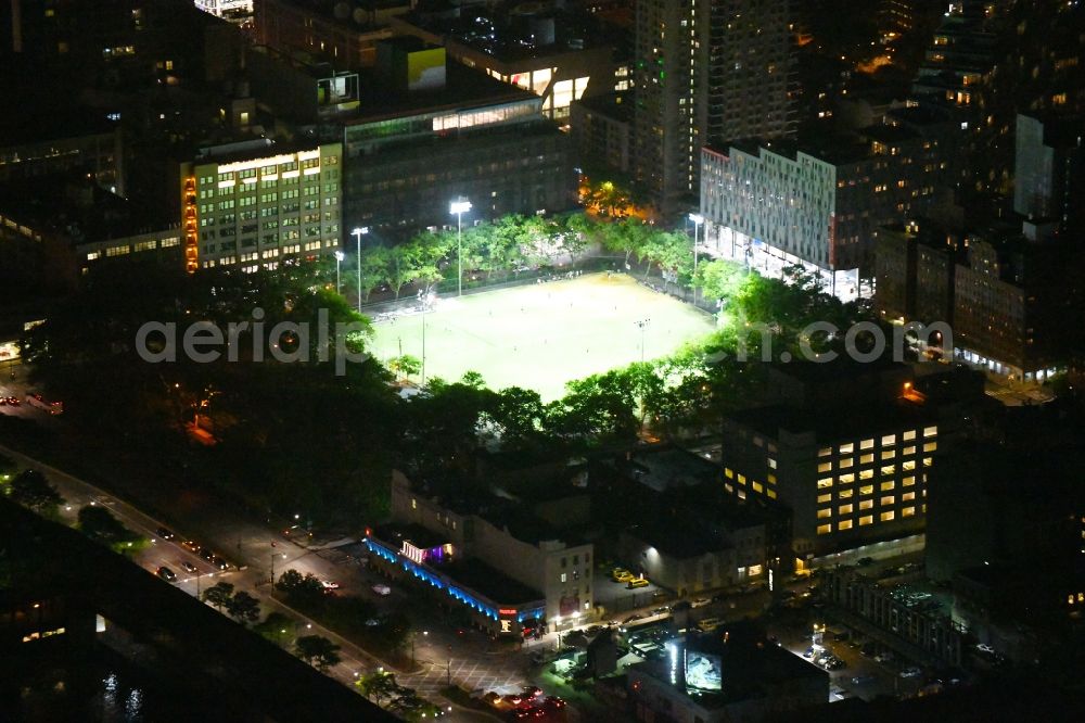 Aerial image at night New York - Night lighting Ensemble of sports grounds De Witt Clinton Park in the district Manhattan in New York in United States of America. In the foreground the Larry Flynt's Hustler Club at the 51st
