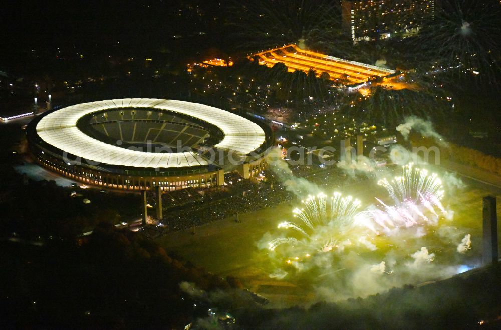 Berlin at night from the bird perspective: Night lighting Fireworks figures in the night sky above the event grounds of Pyronale Fireworks Competition at the Olympic Stadium in the district Charlottenburg in Berlin, Germany