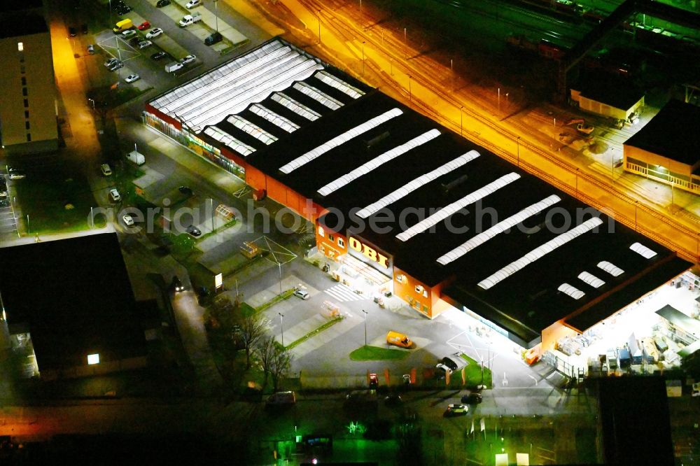 Aerial photograph at night Berlin - Night lighting building of OBI GmbH & Co. Deutschland KG an der Buchberger Strasse im Stadtteil Lichtenberg in Berlin in Germany