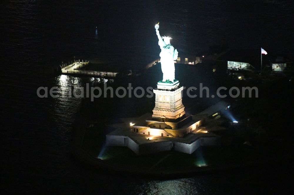 Aerial image at night New York - Night lighting Tourist attraction of the historic monument Freiheitsstatue - Statue of Liberty National Monument in the district Manhattan in New York in United States of America