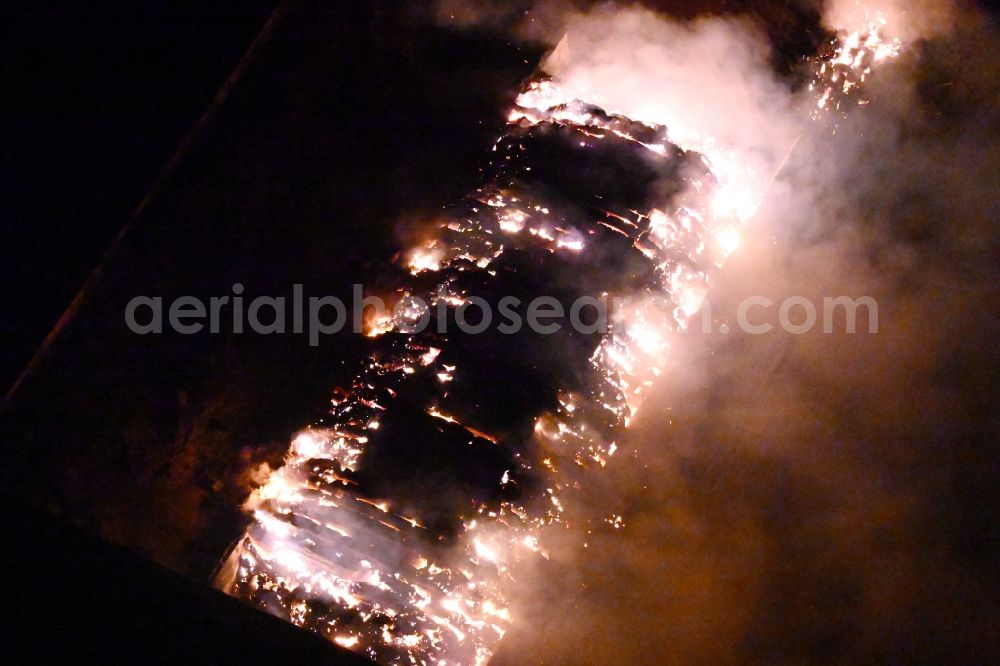 Aerial photograph at night Bad Lauchstädt - Night lighting fire controlled by the fire brigade - major fire in a straw bale silage bale stack on an agricultural storage area on the country road L173 in Bad Lauchstaedt in the state Saxony-Anhalt, Germany