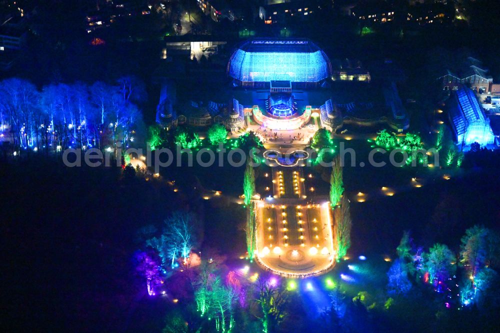 Aerial image at night Berlin - Night lighting main building and greenhouse complex of the Botanical Gardens Berlin-Dahlem in Berlin. The historical glass buildings and greenhouses are dedicated to different areas. The Large Tropical House and the Victoria-House are located in the center