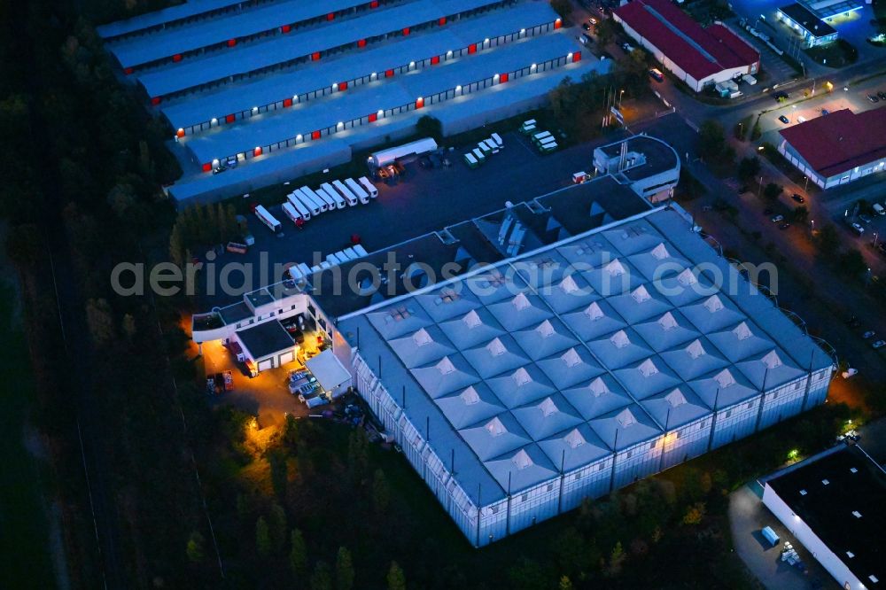 Ahrensfelde at night from the bird perspective: Night lighting warehouses and forwarding building NORMA Zentrallager on Moebel-Huebner-Strasse in Ahrensfelde in the state Brandenburg, Germany