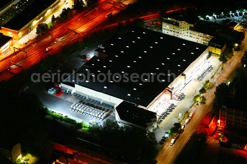 Aerial image at night Berlin - Night lighting warehouses and forwarding building REWE Food Fulfillment Center on street Teilestrasse in the district Tempelhof in Berlin, Germany