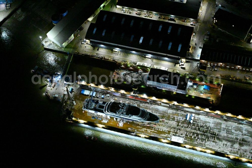 Aerial image at night Hamburg - Night lighting ship's hull of Luxury - yachts for maintenance, conversion and modernization in dry dock on the shipyard site in Hamburg, Germany