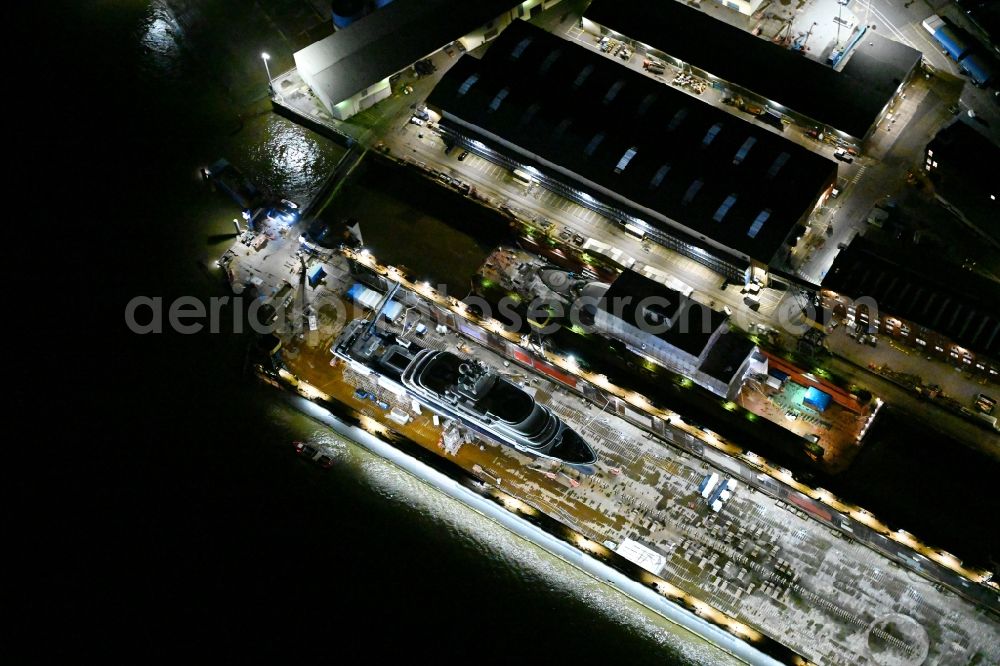Hamburg at night from above - Night lighting ship's hull of Luxury - yachts for maintenance, conversion and modernization in dry dock on the shipyard site in Hamburg, Germany