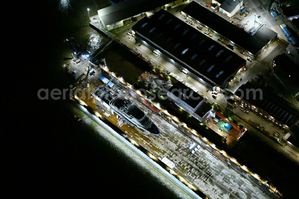 Hamburg at night from the bird perspective: Night lighting ship's hull of Luxury - yachts for maintenance, conversion and modernization in dry dock on the shipyard site in Hamburg, Germany