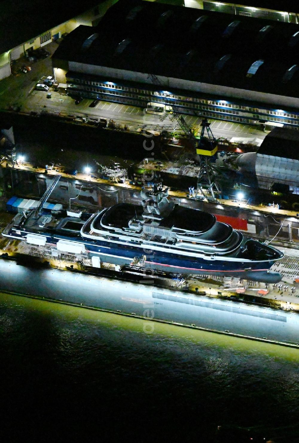 Hamburg at night from the bird perspective: Night lighting ship's hull of Luxury - yachts for maintenance, conversion and modernization in dry dock on the shipyard site in the district Steinwerder in Hamburg, Germany