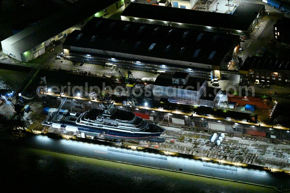 Aerial photograph at night Hamburg - Night lighting ship's hull of Luxury - yachts for maintenance, conversion and modernization in dry dock on the shipyard site in the district Steinwerder in Hamburg, Germany