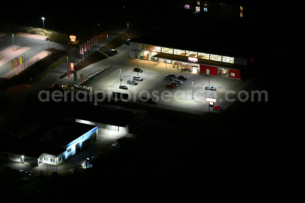Aerial photograph at night Bürgel - Night lighting building complex of local supply center REWE on street In den Satteln in Buergel in the state Thuringia, Germany