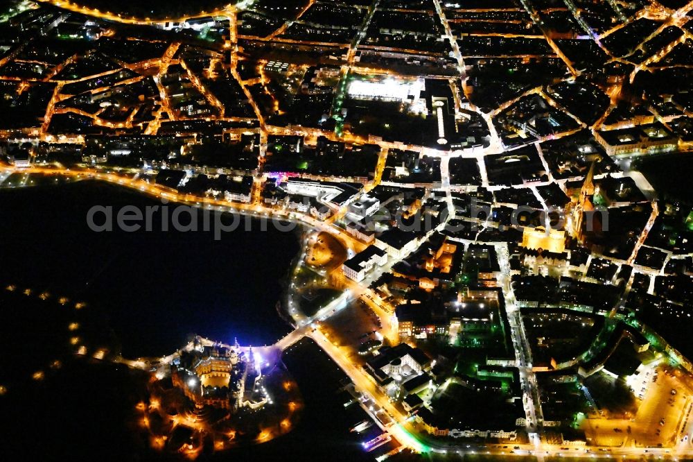 Aerial photograph at night Schwerin - Night lights and illumination of the domed towers of the Schwerin Castle and the Castle Church in the castle garden on the Burgsee on the Castle Island, the seat of the state parliament in the state capital of Schwerin in Mecklenburg-Western Pomerania