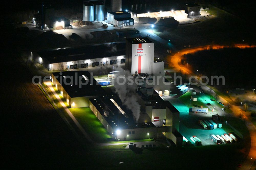 Aerial photograph at night Heidegrund - Night lighting high silo and grain storage with adjacent storage Thueringer Muehlenwerke GmbH on Muehlenstrasse in the district Weickelsdorf in Heidegrund in the state Saxony-Anhalt, Germany