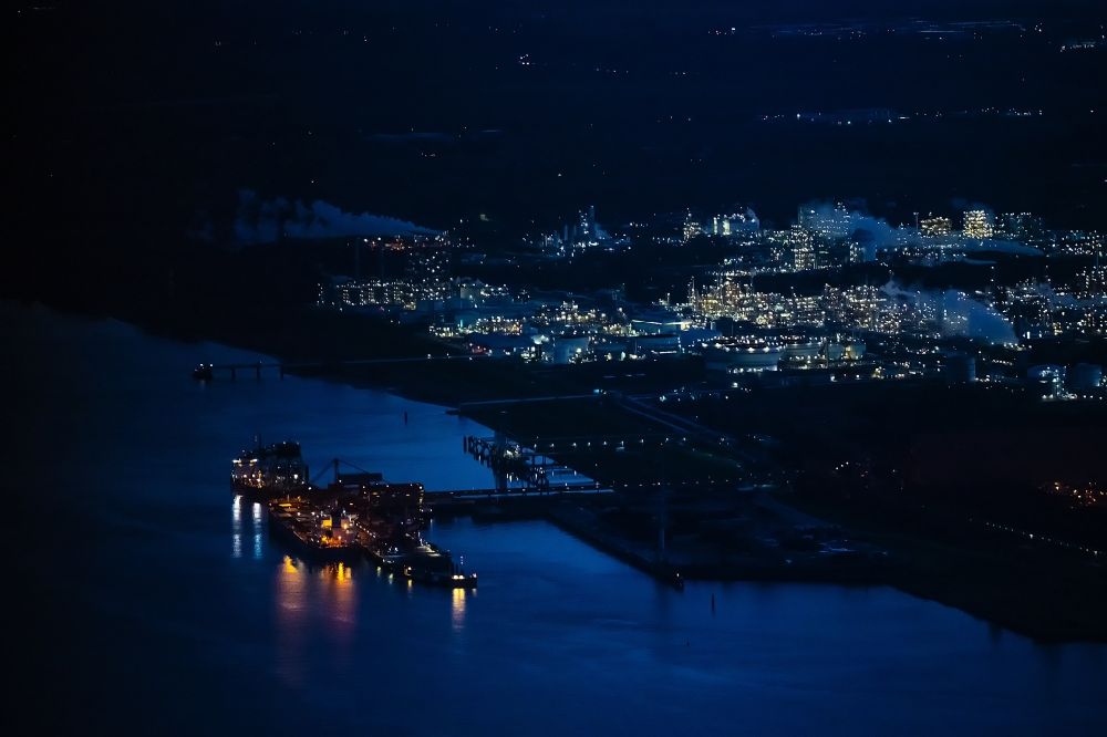 Aerial photograph at night Stade - Night lighting port facility Stader Seehafen AOS am Buetzflether Sand in Buetzfleth in the state Lower Saxony, Germany. The Hanseatic Energy Hub is to be built on the green space by 2026. The planned terminal for the import of liquefied natural gas (LNG) will be integrated into the existing industrial park