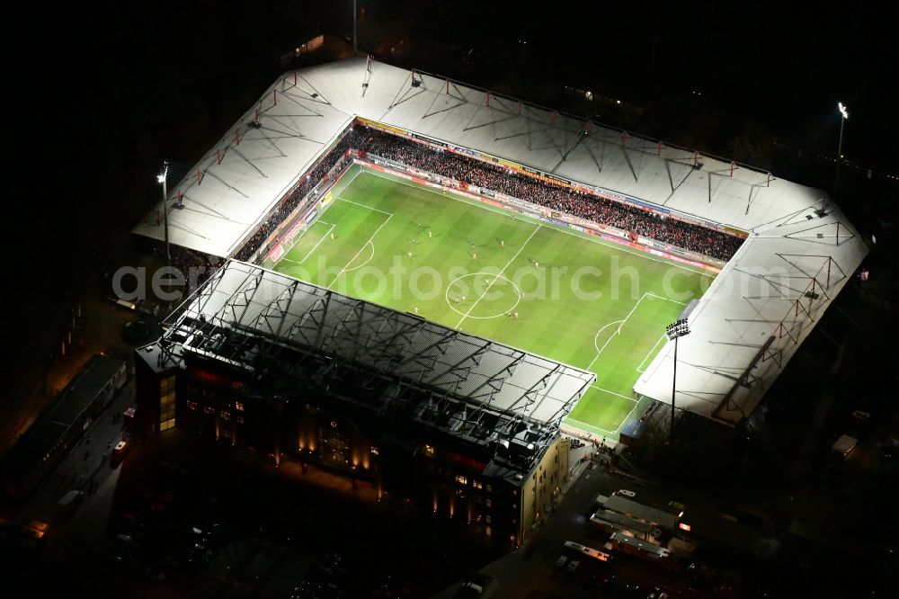 Berlin at night from the bird perspective: Night lighting view of the football stadium Alte Foersterei with its new grandstand the district of Koepenick in Berlin. The pitch is homestead for the football games of FC Union Berlin