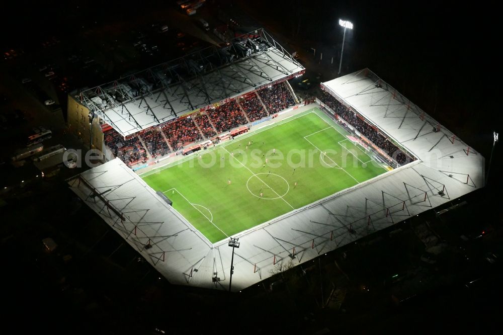 Berlin at night from the bird perspective: Night lighting view of the football stadium Alte Foersterei with its new grandstand the district of Koepenick in Berlin. The pitch is homestead for the football games of FC Union Berlin
