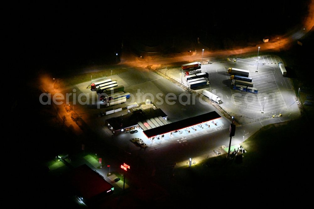 Aerial image at night Kleinhelmsdorf - Night lighting gas station TotalEnergies Autohof for sale of petrol and diesel fuels and mineral oil trade on street Im Heidegrund Sued - Lindenstrasse in Kleinhelmsdorf in the state Saxony-Anhalt, Germany