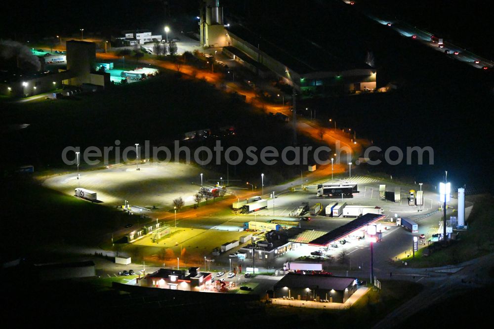 Kleinhelmsdorf at night from above - Night lighting gas station TotalEnergies Autohof for sale of petrol and diesel fuels and mineral oil trade on street Im Heidegrund Sued - Lindenstrasse in Kleinhelmsdorf in the state Saxony-Anhalt, Germany