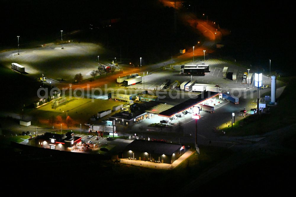 Kleinhelmsdorf at night from the bird perspective: Night lighting gas station TotalEnergies Autohof for sale of petrol and diesel fuels and mineral oil trade on street Im Heidegrund Sued - Lindenstrasse in Kleinhelmsdorf in the state Saxony-Anhalt, Germany