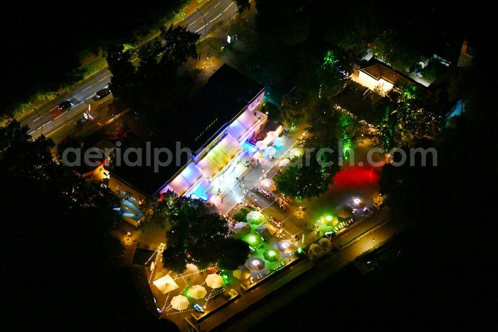 Aerial image at night Berlin - Night lighting tables and benches of open-air restaurant Haus Zenner on street Alt-Treptow in the district Treptow in Berlin, Germany