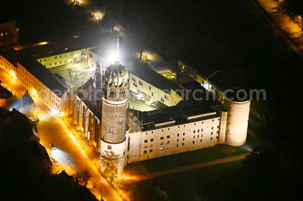 Lutherstadt Wittenberg at night from the bird perspective: Night lighting castle church of Wittenberg. The castle with its 88 m high Gothic tower at the west end of the town is a UNESCO World Heritage Site. It gained fame as the Wittenberg Augustinian monk and theology professor Martin Luther spread his disputation