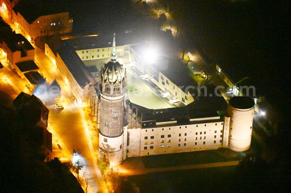 Aerial photograph at night Lutherstadt Wittenberg - Night lighting castle church of Wittenberg. The castle with its 88 m high Gothic tower at the west end of the town is a UNESCO World Heritage Site. It gained fame as the Wittenberg Augustinian monk and theology professor Martin Luther spread his disputation