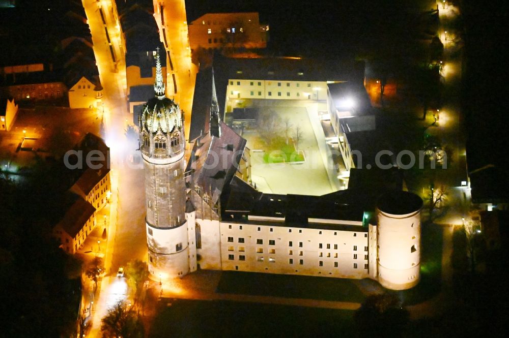 Aerial image at night Lutherstadt Wittenberg - Night lighting castle church of Wittenberg. The castle with its 88 m high Gothic tower at the west end of the town is a UNESCO World Heritage Site. It gained fame as the Wittenberg Augustinian monk and theology professor Martin Luther spread his disputation