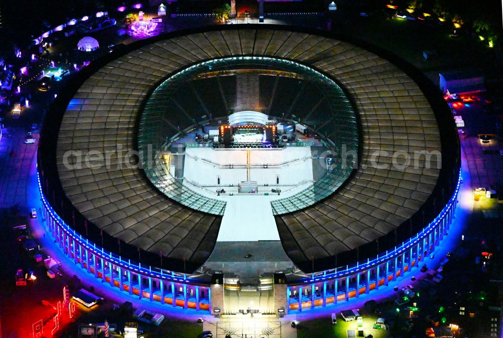 Aerial image at night Berlin - Night lights and lighting of construction work in preparation for the festival Lollapalooza sports venue area of the arena of the Olympic Stadium in Berlin