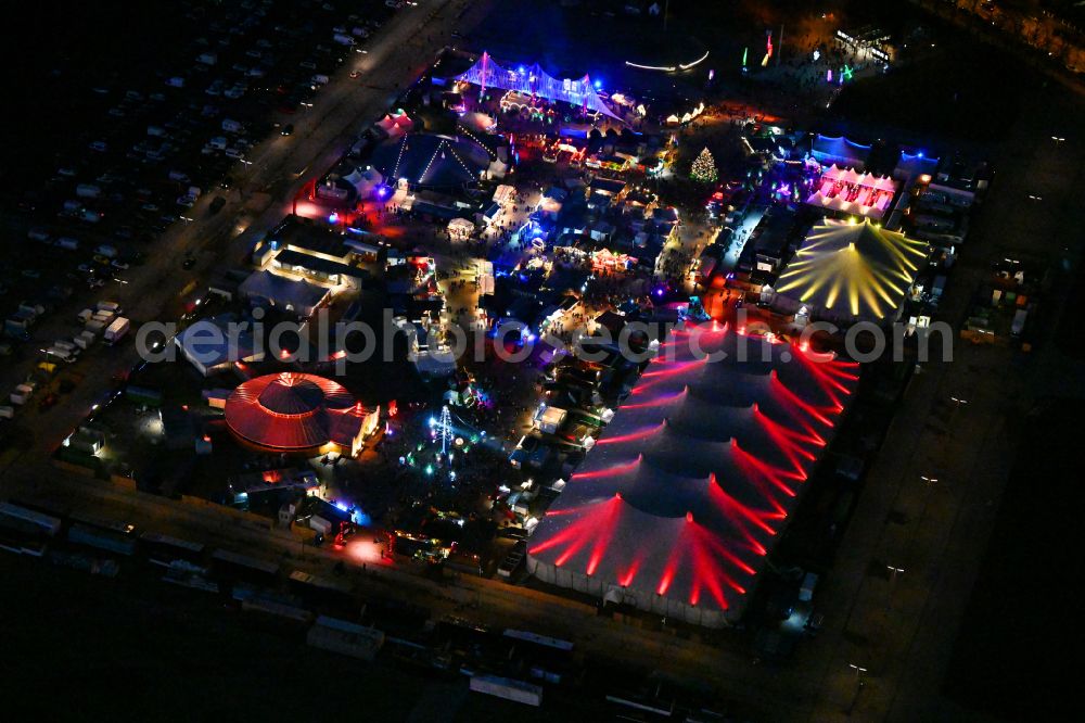 Aerial image at night München - Night lighting christmassy market event grounds and sale huts and booths on Veranstaltungsgelaende of Theresienwiese on street Wirtsbudenstrasse in Munich in the state Bavaria, Germany