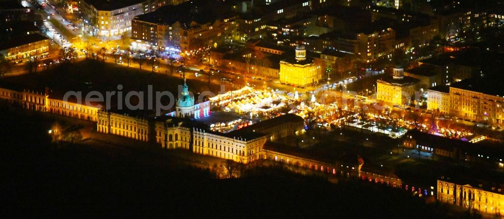 Aerial image at night Berlin - Night lighting Christmassy market event grounds and sale huts and booths on Schloss Charlottenburg in the district Charlottenburg in Berlin, Germany