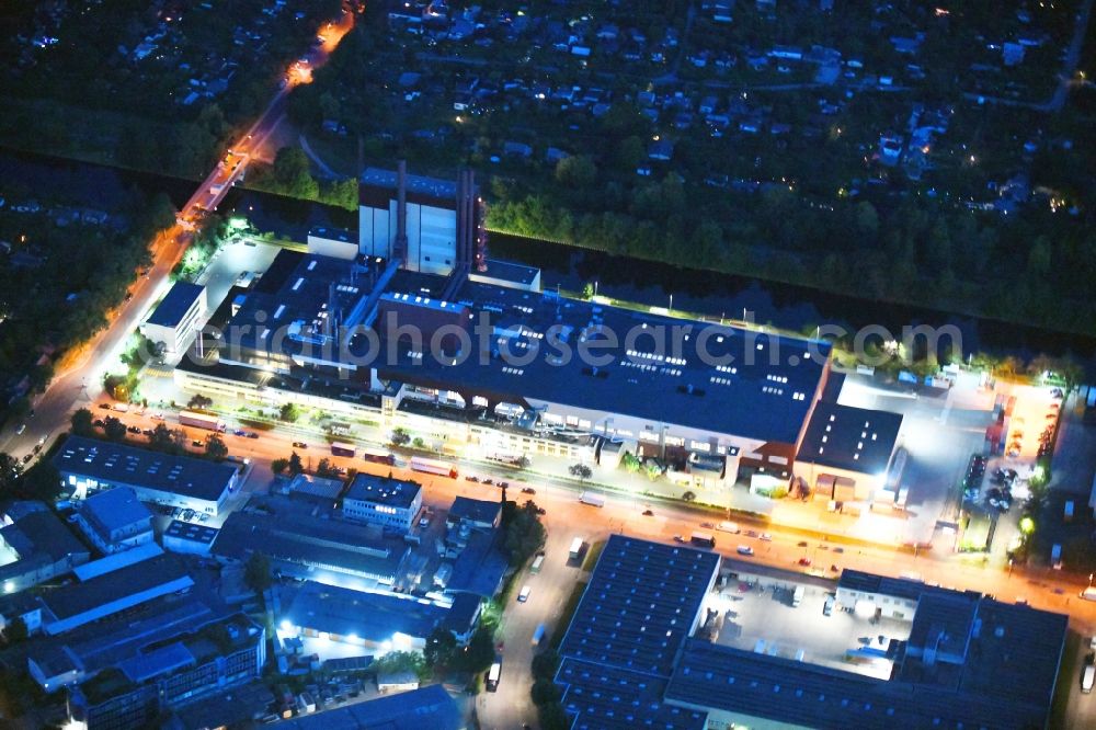 Berlin at night from the bird perspective: Night lighting building and production halls on the premises of Kaffeegrosshaendler Jacobs Douwe Egberts in Berlin, Germany