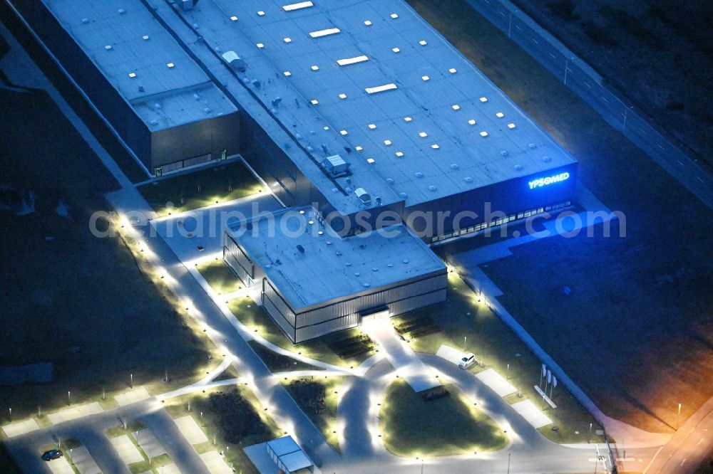 Aerial image at night Schwerin - Night lighting building and production halls on the premises of Ypsomed Produktion GmbH on street Ludwig-Boelkow-Strasse in Schwerin in the state Mecklenburg - Western Pomerania, Germany