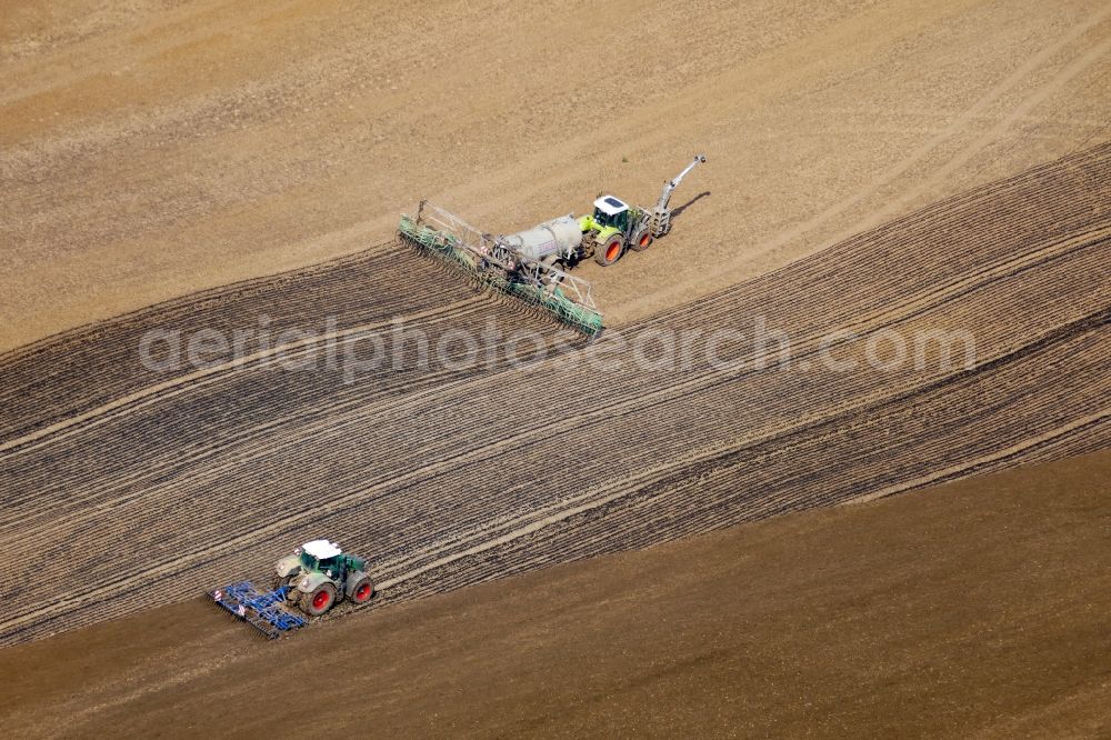 Aerial image Göttingen - Spraying manure as fertilizer with tractor and tank trailer on agricultural fields in Goettingen in the state Lower Saxony, Germany