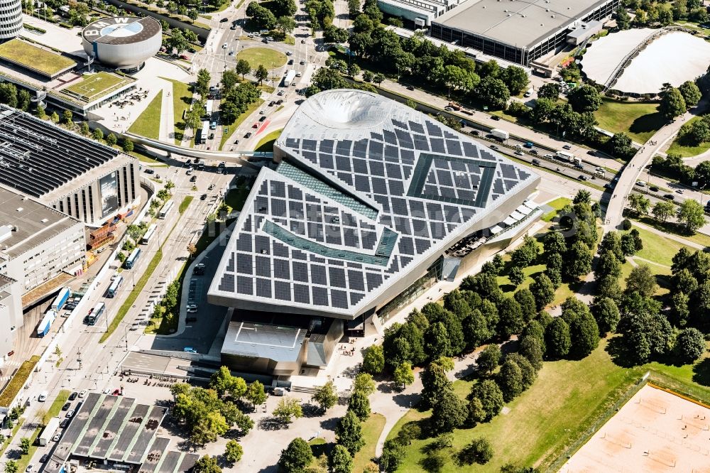 Aerial image München - The BMW Welt is a combined exhibition, delivery, adventure, museum and event venue in Munich in Bavaria and is part of the corporate headquarters of the car manufacturer BMW. In the so-called brand world, an exhibition pavilion, the current models of BMW, MINI, Rolls-Royce Motor Cars and BMW Motorrad, innovations and technology are presented. On the roof of the multifunctional building a solar power plant produces electricity. Architect of the building are Prof. Wolf D. Prix and the architectural firm Coop Himmelb (l) au