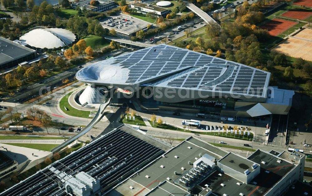 München from above - The BMW Welt is a combined exhibition, delivery, adventure, museum and event venue in Munich in Bavaria and is part of the corporate headquarters of the car manufacturer BMW. In the so-called brand world, an exhibition pavilion, the current models of BMW, MINI, Rolls-Royce Motor Cars and BMW Motorrad, innovations and technology are presented. On the roof of the multifunctional building a solar power plant produces electricity
