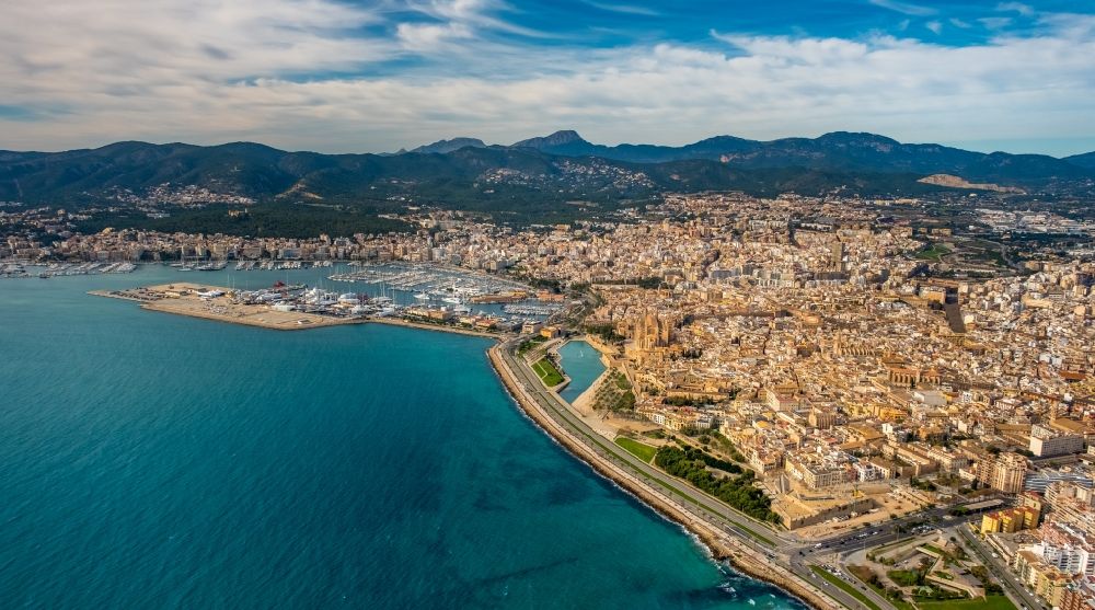 Aerial image Palma - Water surface at a bay along the marine coast Punta des Gas along the Avenida de Gabriel Roca in the district Llevant de Palma District with the port in the background in Palma in Balearic island Mallorca, Spain