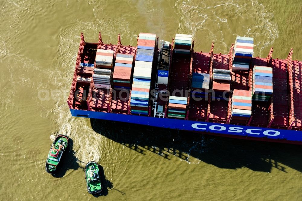 Hamburg from the bird's eye view: Container ship with tugboats in the port in Hamburg, Germany